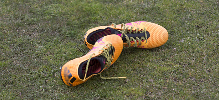 orangea fotbollsskor som ligger på underlag av gräs